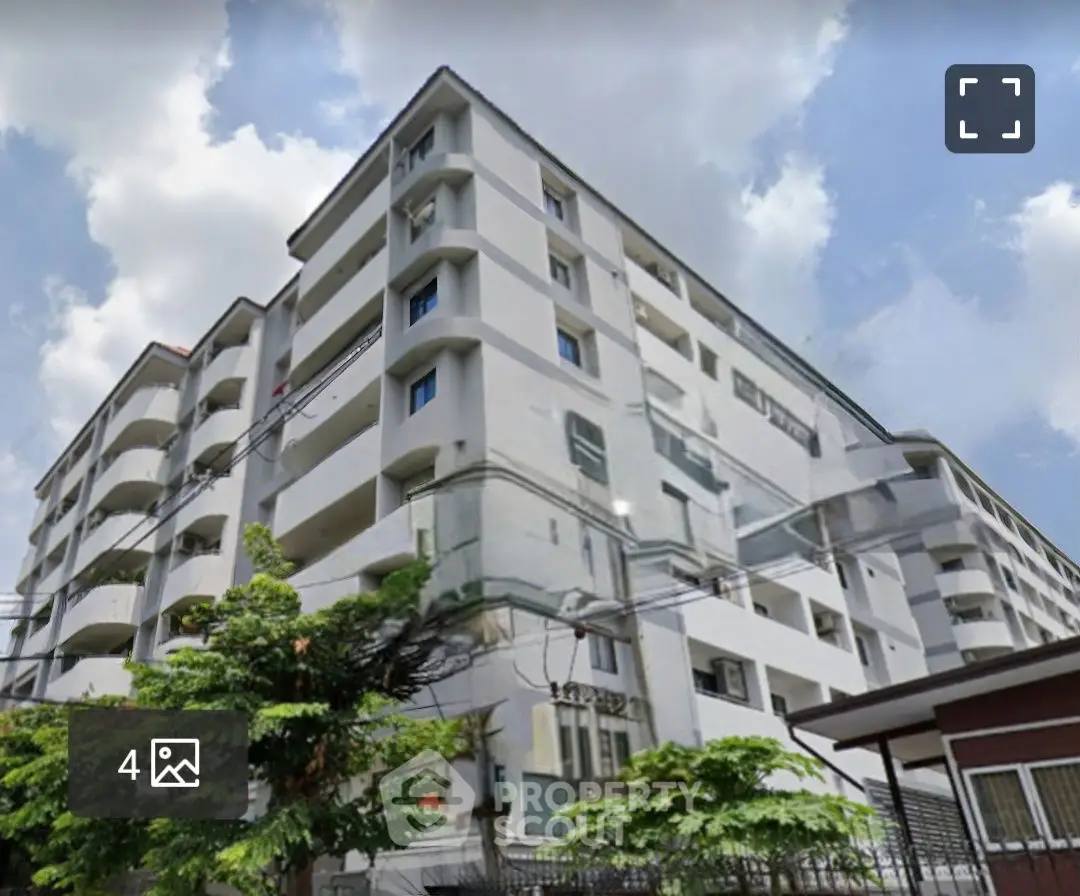 Modern multi-story apartment building with balconies and lush greenery, perfect for urban living.