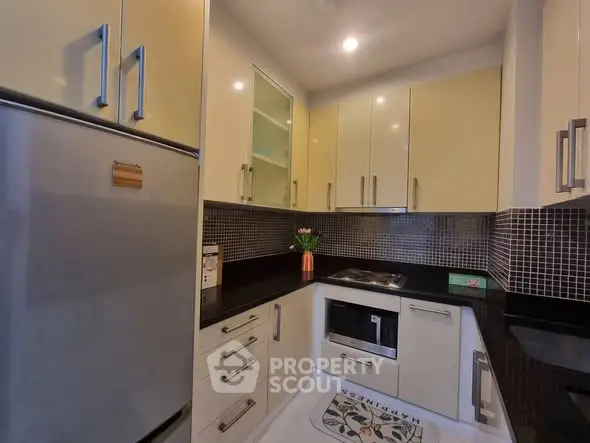 Modern kitchen with sleek cabinetry and built-in appliances in a cozy apartment.