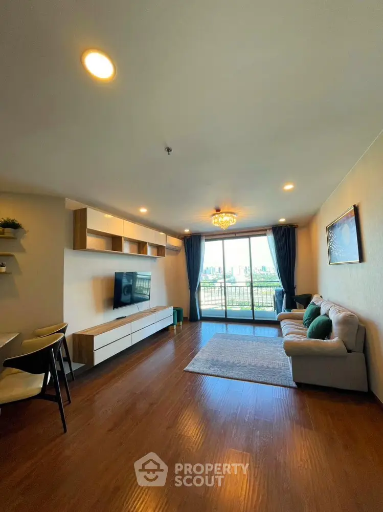 Spacious living room with modern decor and large balcony offering city views.