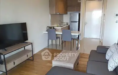 Modern open-plan living room with kitchen, featuring sleek furniture and wooden flooring.