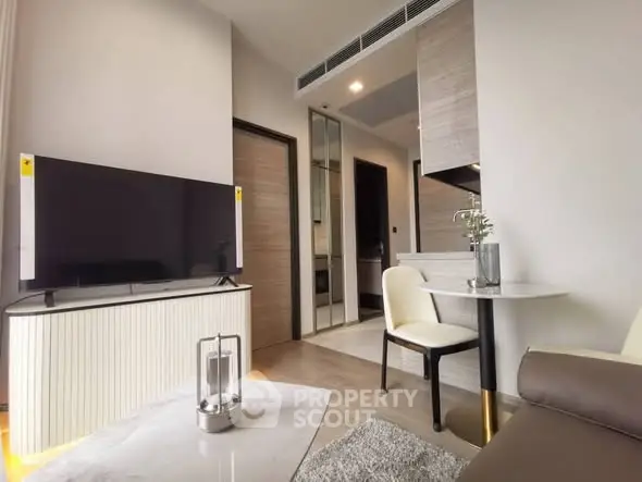 Modern living room with sleek TV and stylish furniture in a cozy apartment.