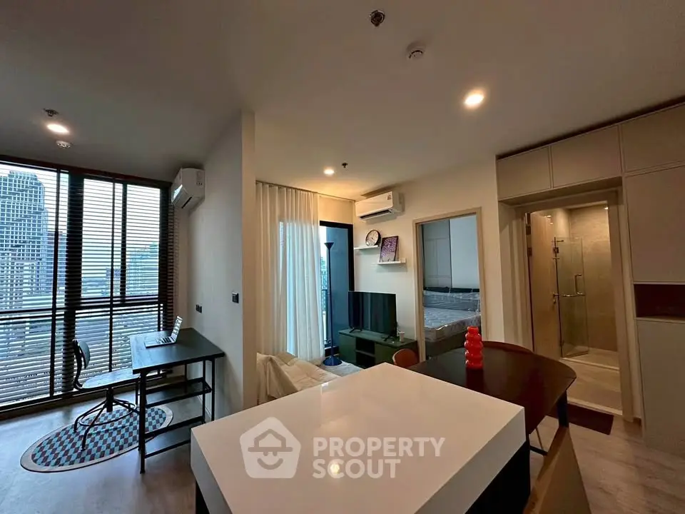 Modern open-plan living room with city view, featuring sleek furniture and natural light.