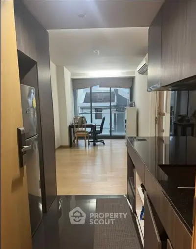Modern apartment interior with sleek kitchen and dining area, featuring large windows and stylish furnishings.