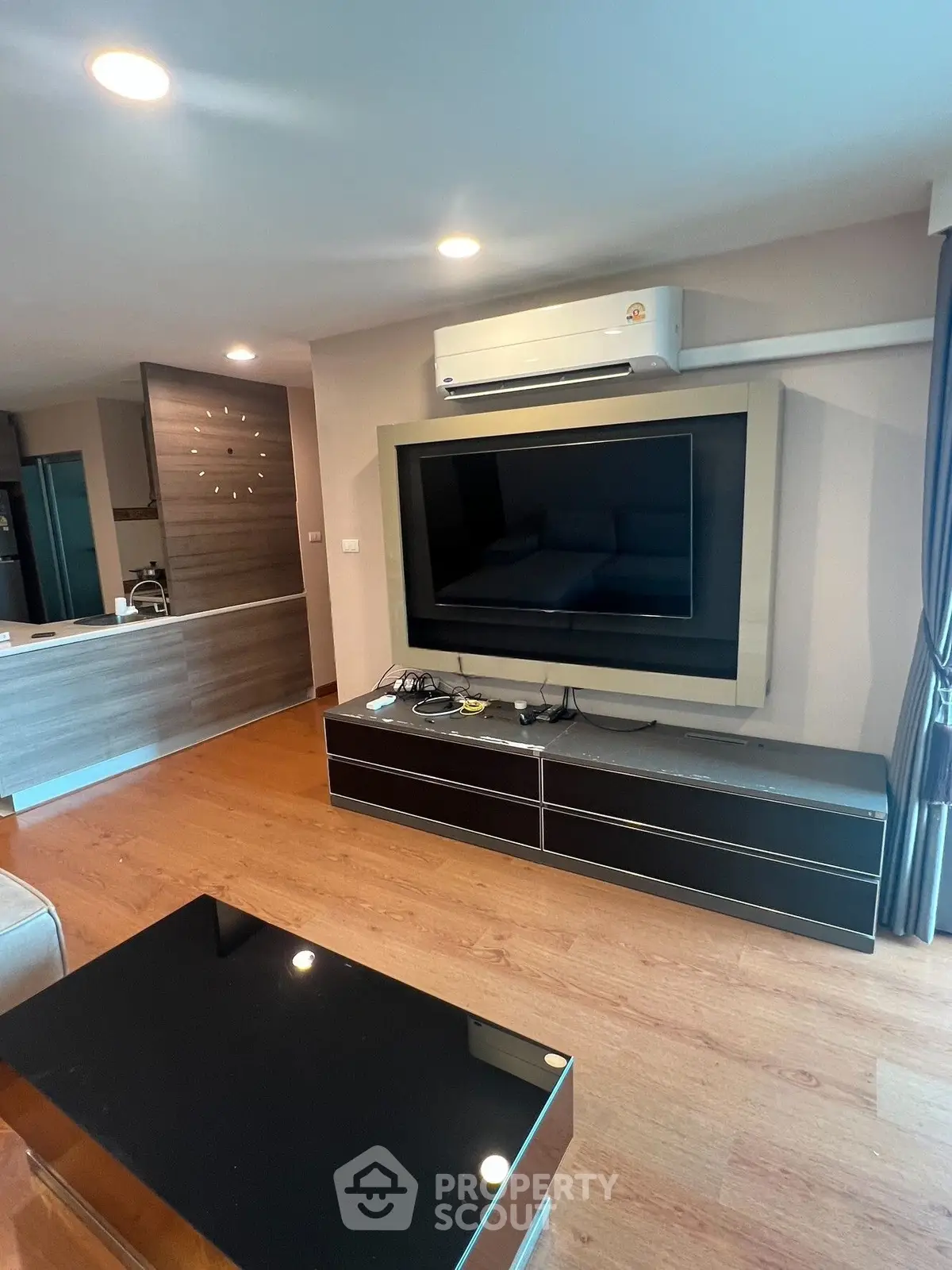 Modern living room with sleek TV unit and air conditioning, featuring wooden flooring and contemporary decor.