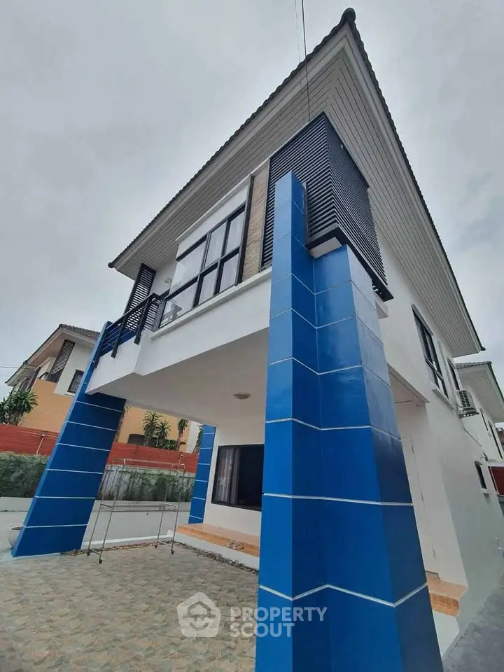 Modern two-story house with striking blue pillars and contemporary design