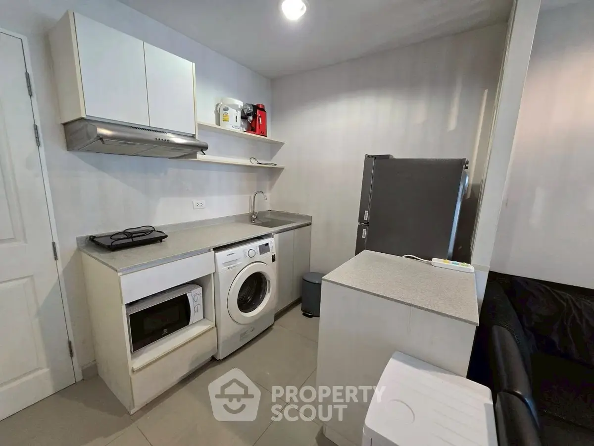 Modern compact kitchen with appliances including washing machine and fridge, ideal for urban living.