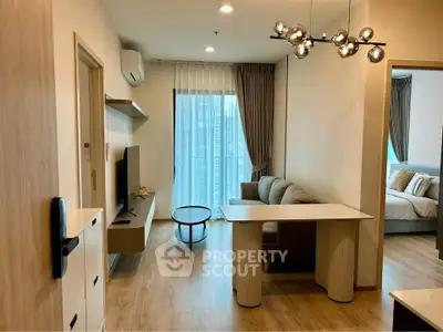 Modern living room with stylish decor and natural light, featuring a cozy sofa and sleek TV setup.
