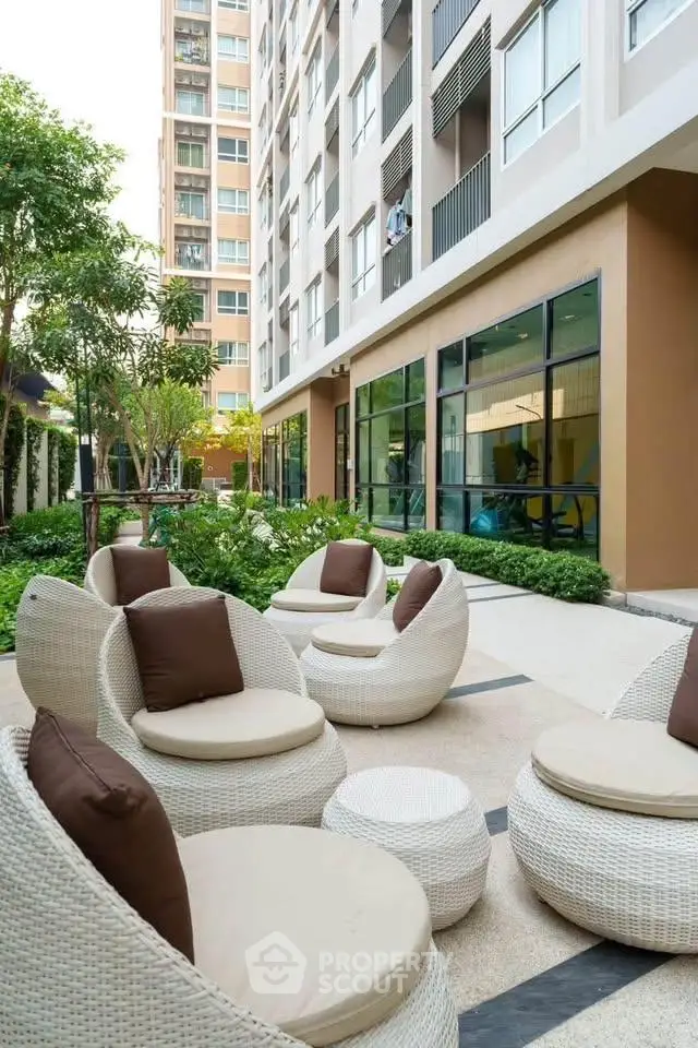 Modern apartment building with stylish outdoor seating area and lush greenery.