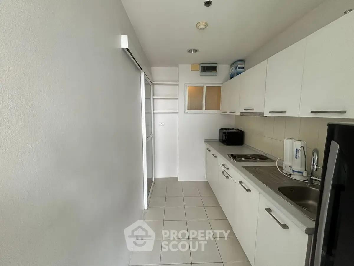 Modern kitchen with sleek white cabinetry and tiled flooring in a compact layout.