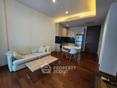 Modern living room with cozy sofa and open kitchen layout, featuring sleek wooden flooring and contemporary design.