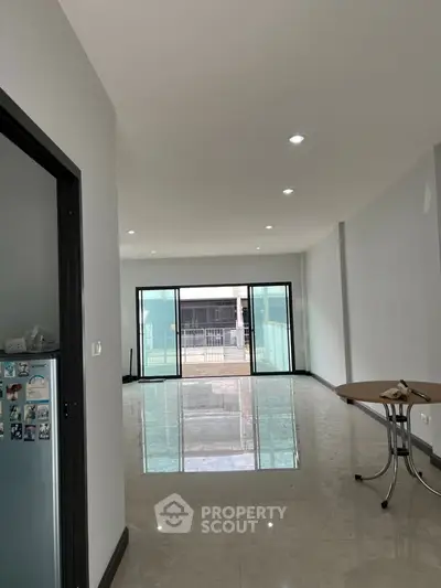 Spacious modern living room with large windows and glossy floors, perfect for natural light and open living.