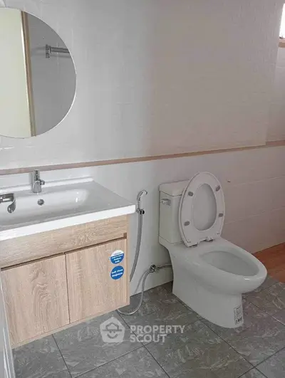 Modern bathroom with sleek sink and toilet, featuring neutral tones and stylish design.