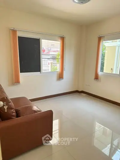 Bright living room with large windows and a cozy brown sofa, perfect for relaxation.