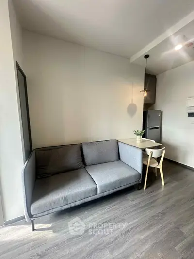 Modern living room with sleek gray sofa and dining area in stylish apartment.