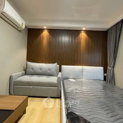 Cozy bedroom with modern furniture and elegant lighting, featuring a comfortable bed and stylish sofa.
