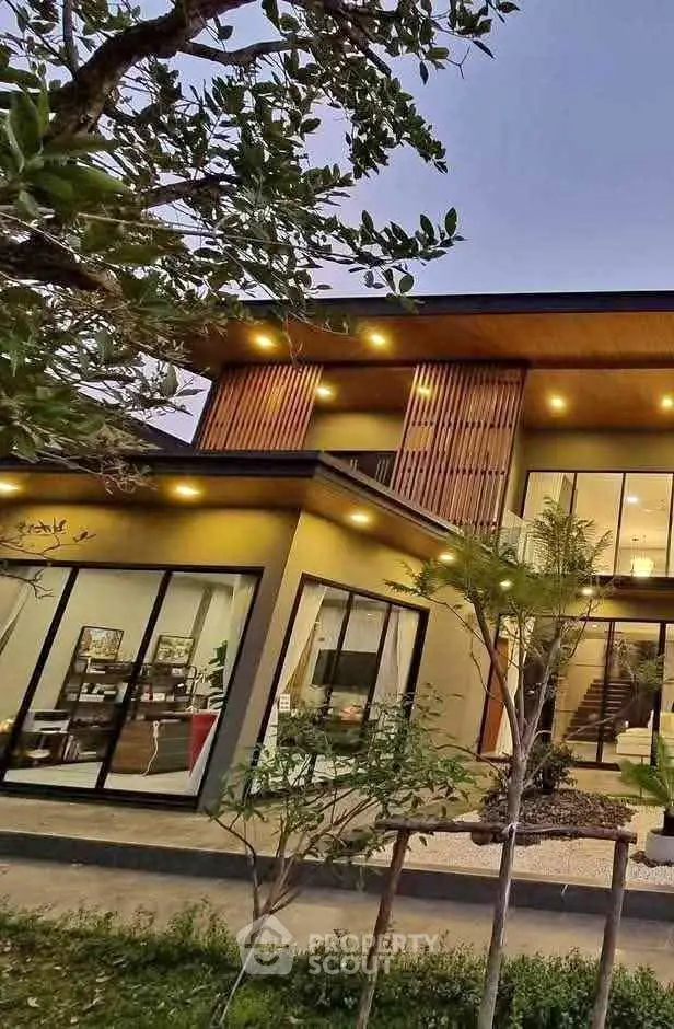 Modern two-story house with large windows and lush garden