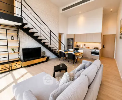 Modern open-plan living room with stylish staircase and kitchen in a bright apartment