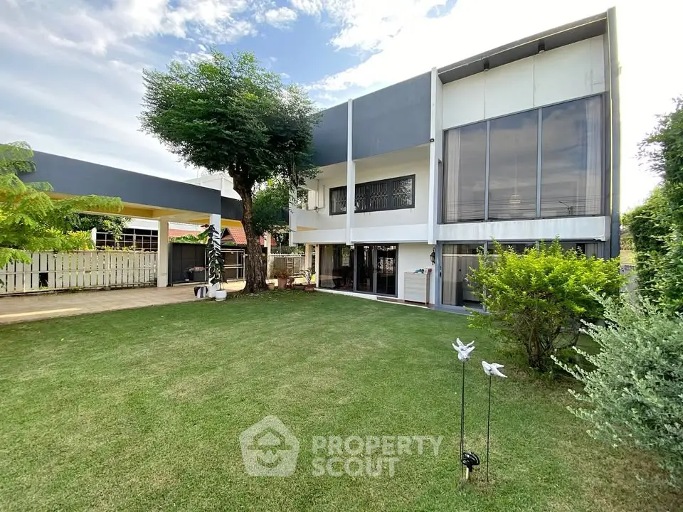 Modern two-story home with spacious green lawn and large windows