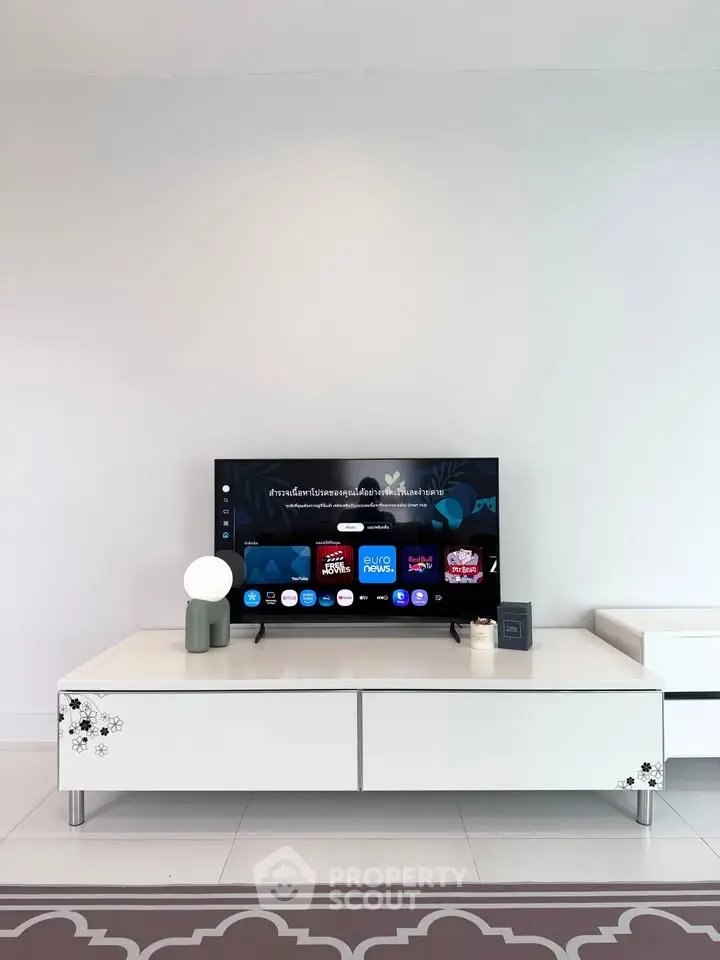 Modern living room with sleek TV setup and stylish white furniture.