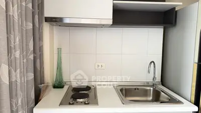 Compact kitchen with electric stove and sleek sink, ideal for modern apartments.