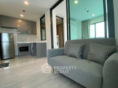 Modern open-layout living room with sleek kitchen and cozy sofa.