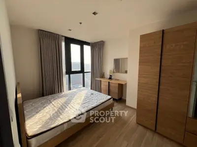 Spacious bedroom with large window and wooden furniture, offering a cozy and inviting atmosphere.