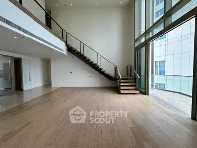 Spacious modern living room with high ceilings and large windows opening to a balcony.