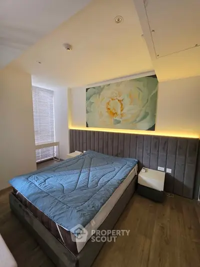 Modern bedroom with stylish decor and cozy lighting, featuring a large bed and elegant wall art.