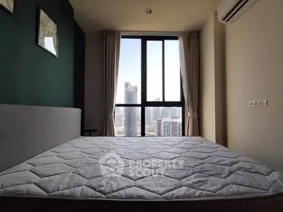Modern bedroom with large window offering stunning city view in high-rise apartment.