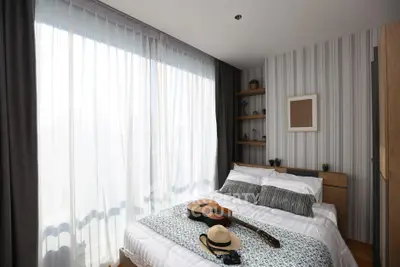 Cozy bedroom with large window, stylish decor, and natural light, perfect for relaxation and comfort.