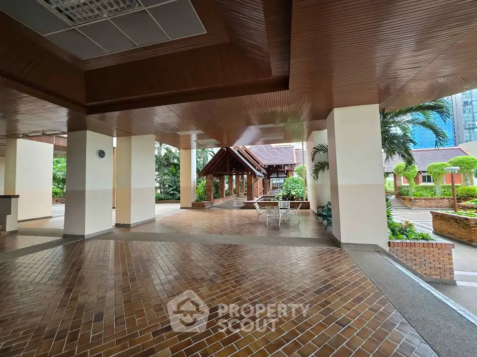 Spacious building entrance with elegant brick flooring and lush greenery