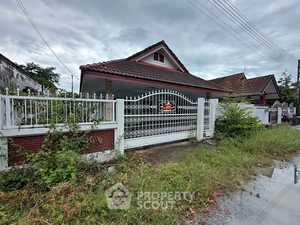 Charming single-story house with red roof and gated entrance in a serene neighborhood.