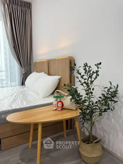 Cozy bedroom with modern decor, featuring a wooden bed, stylish side table, and potted plant for a serene ambiance.