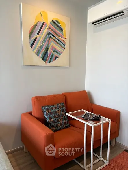 Cozy living room with vibrant orange sofa and modern wall art, perfect for relaxation.