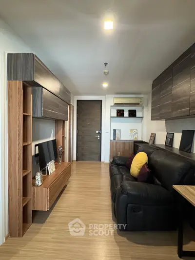 Modern living room with sleek wooden furniture and cozy black leather sofa