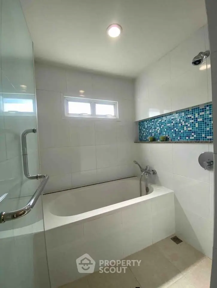 Modern bathroom with sleek bathtub and stylish mosaic tile accent wall.