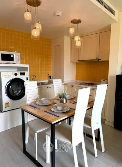 Modern kitchen with dining area, featuring washing machine and stylish lighting.