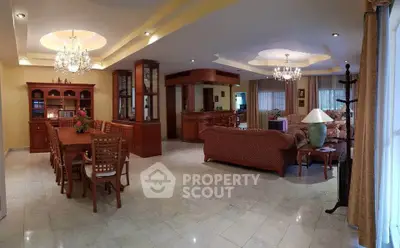 Spacious living and dining area with elegant chandeliers and classic wooden furniture.