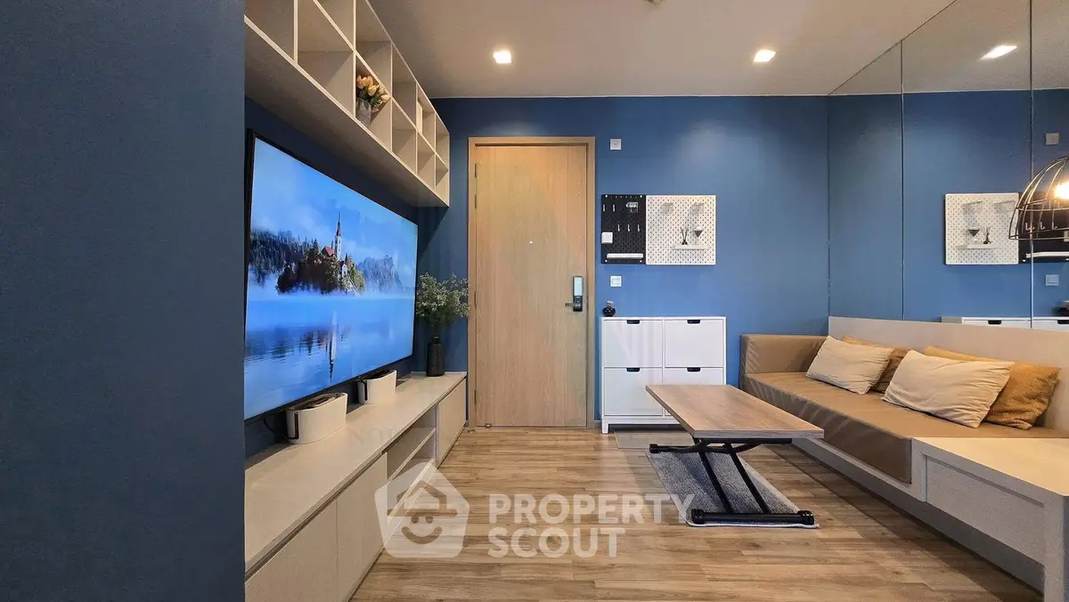 Modern living room with blue walls, large TV, and cozy seating area.