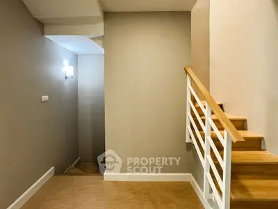 Modern staircase with wooden steps and white railing in a minimalist interior.