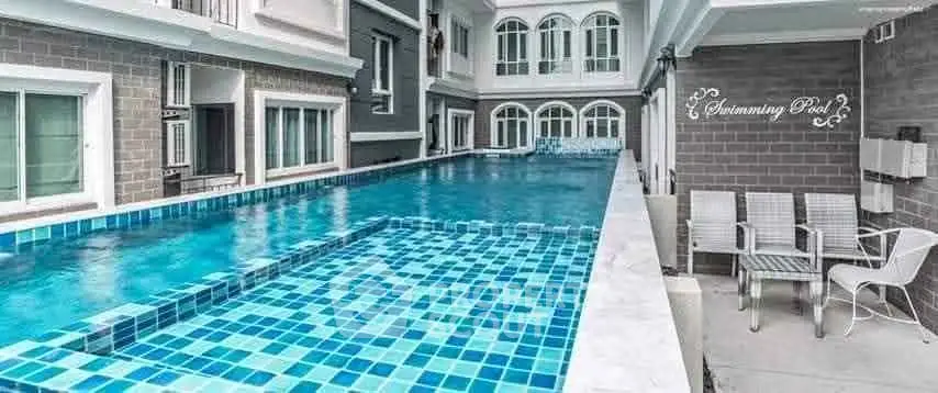 Luxurious swimming pool area in modern residential building with elegant design and seating area.