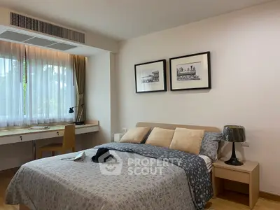Cozy bedroom with stylish decor and natural light, featuring a comfortable bed and a work desk by the window.