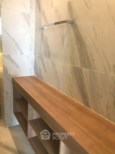 Luxurious marble bathroom with elegant wooden shelving and modern design.