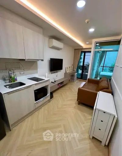Modern living room with open kitchen and balcony access in stylish apartment.