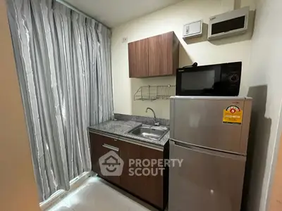 Compact kitchen with modern appliances and sleek cabinetry in cozy apartment.