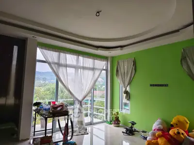 Spacious living room with large windows and scenic view, featuring modern ceiling design and vibrant green walls.