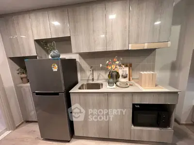 Modern kitchen with sleek cabinetry, stainless steel fridge, and built-in microwave, perfect for contemporary living.