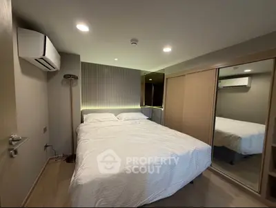 Modern bedroom with mirrored closet and ambient lighting, featuring a cozy double bed and sleek air conditioning unit.