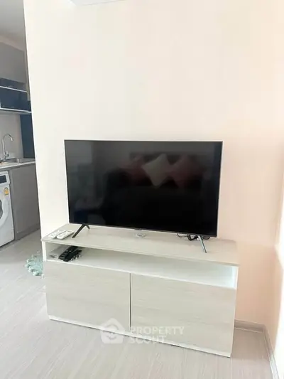 Modern living room with sleek TV stand and washing machine in open layout.