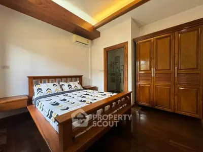 Spacious bedroom with wooden furniture and modern design, featuring a large bed and built-in wardrobe.